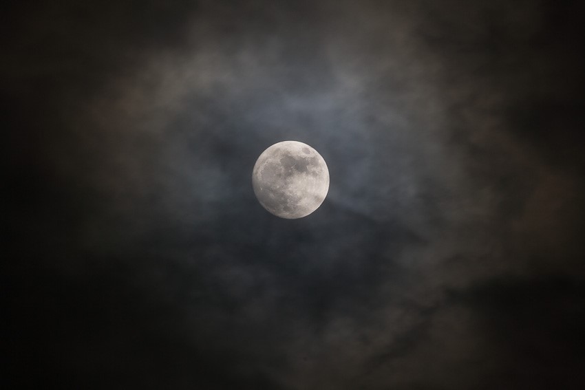 Photo of a full moon with clouds against a black sky