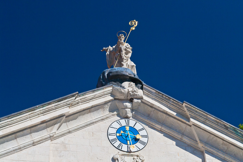 Photo of a statue of a saint on the roof of the church of St. George, Weltenburg Abbey, Bavaria, Germany with a blue sky