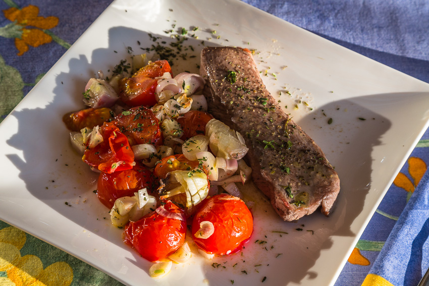 Photo of a roasted lamb filet with roasted tomatoes and shallots on a plate
